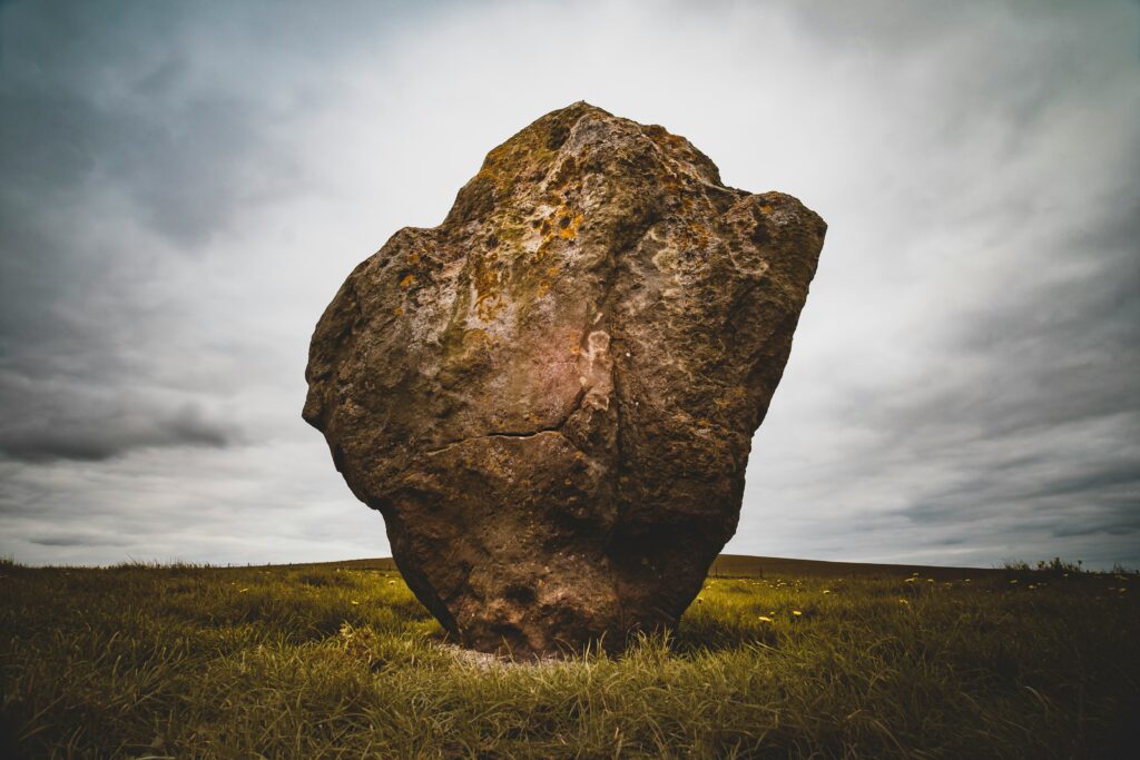 An image of a very large boulder balanced on a green field by photographer Zoltan Tasi